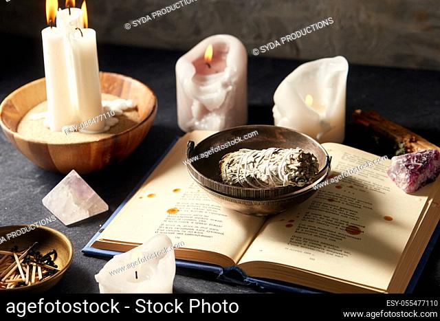 magic book, sage, burning candles and ritual staff