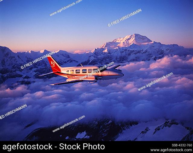 K2 Aviation's Piper Navajo Chieftain flying above clouds east of the Kahiltna Glacier of 20, 320 foot Mount McKinley or Denali beyond, Denali National Park