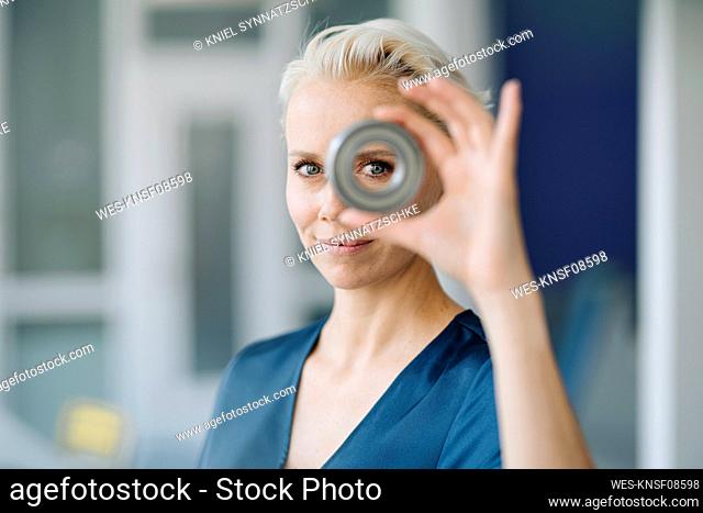 Close-up of confident businesswoman looking through object in office