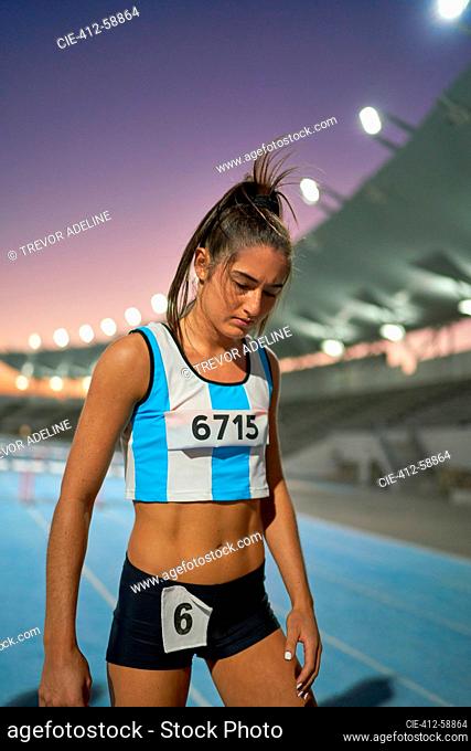 Tired female track and field athlete on track after competition