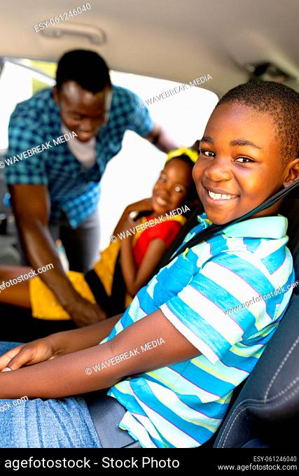 Portrait of smiling african american siblings with father teaching to wear seat belt in car