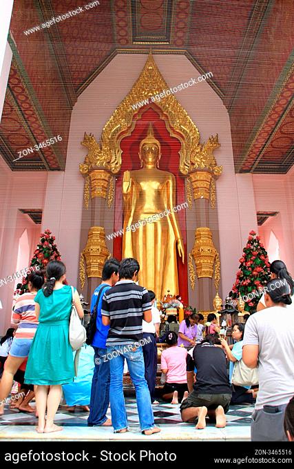 People pray near golden Buddha in temple, Chedi Phra Pathom, Thailand