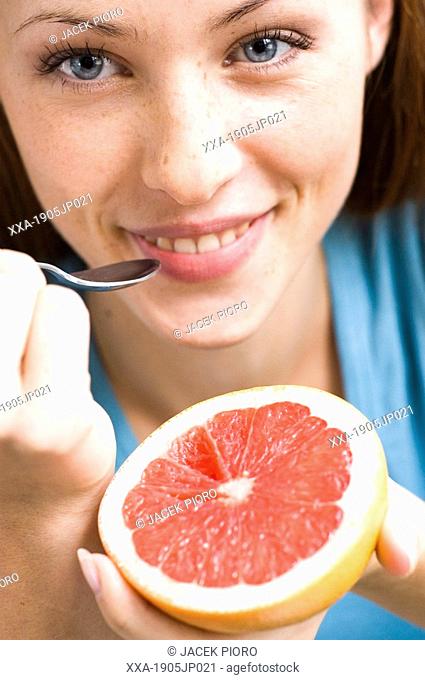 young woman eating half of grapefruit