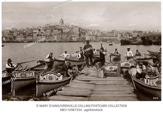 Ferryboats and boatmen moored close to the Bridge and Quay at Galata, Constantinople, Turkey, ready to provide transport across the Golden Horn