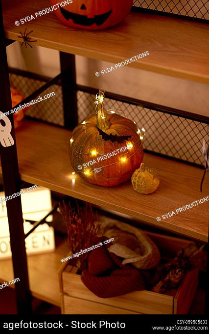 halloween pumpkin with garland lights on shelf