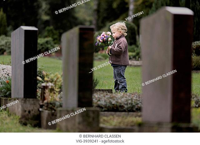 GERMANY, WRIEDEL, Boy, 3 years, with flowers at a grave - WriedelGermany, 16/10/2013