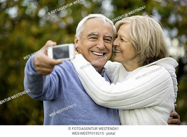 Portrait of happy senior couple taking self-portrait with smartphone