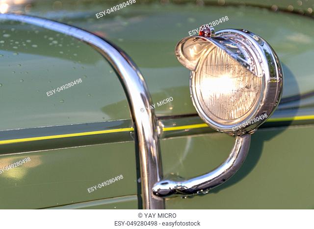 Headlamp and chrome decoration detail on hood of vintage classic oldtimer car