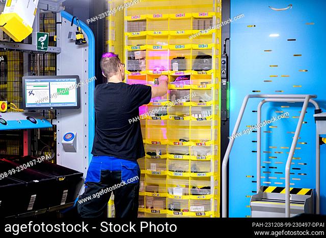 07 December 2023, Lower Saxony, Großenkneten: An employee fills a shelf unit in Amazon's new logistics center at the former Ahlhorn airbase with items in the...