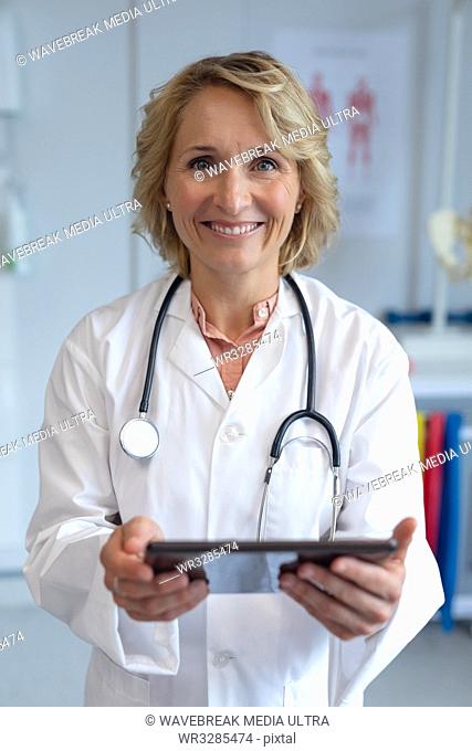 Front view of Caucasian female doctor with stethoscope around her neck using digital tablet in the hospital