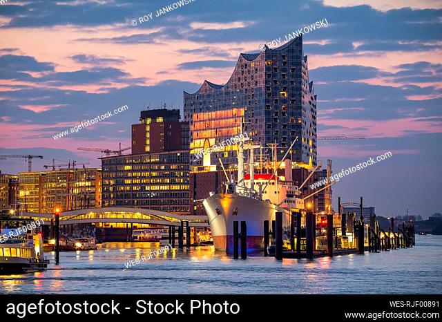 Germany, Hamburg, Ship docked in HafenCity at dawn with Elbphilharmonie in background