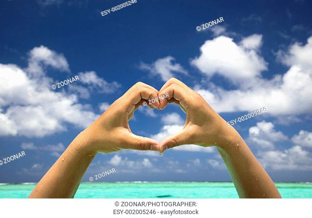 hand forming a heart on tropical beach background