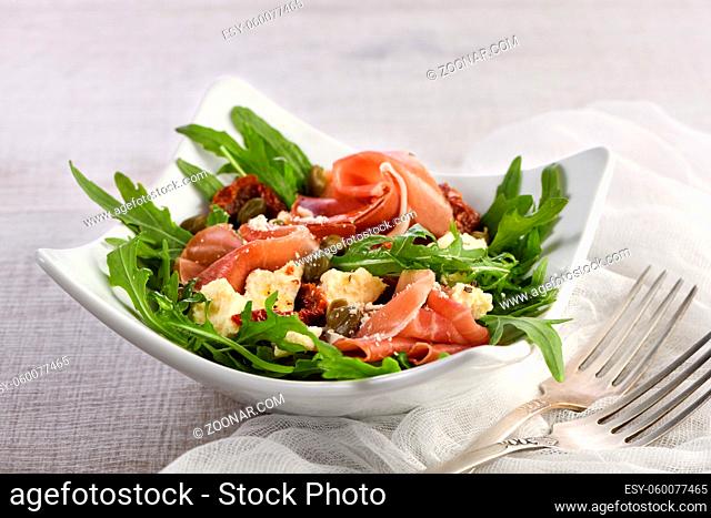 Arugula salad, prosciutto with sun-dried tomatoes, slices of mozzarella, capers, seasoned with olive butter and parmesan