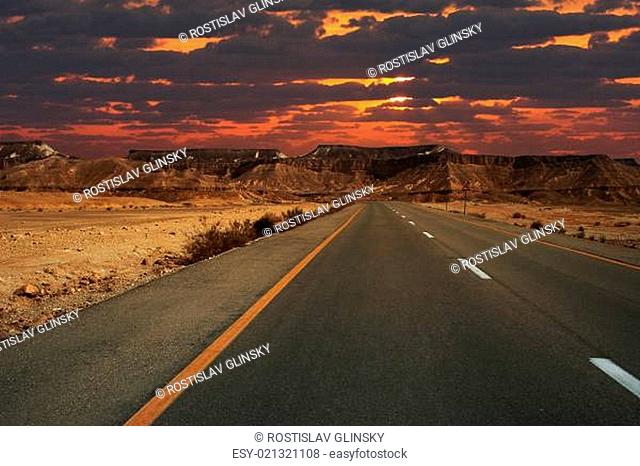 Beautiful sunset over mountains and highway running through Ramon crater in Isra