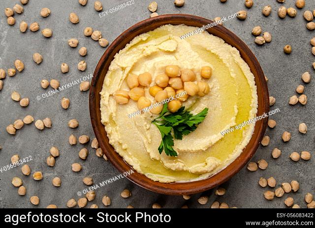 Flat lay view at hummus topped with green coriander leaves on stone table covered with chickpeas