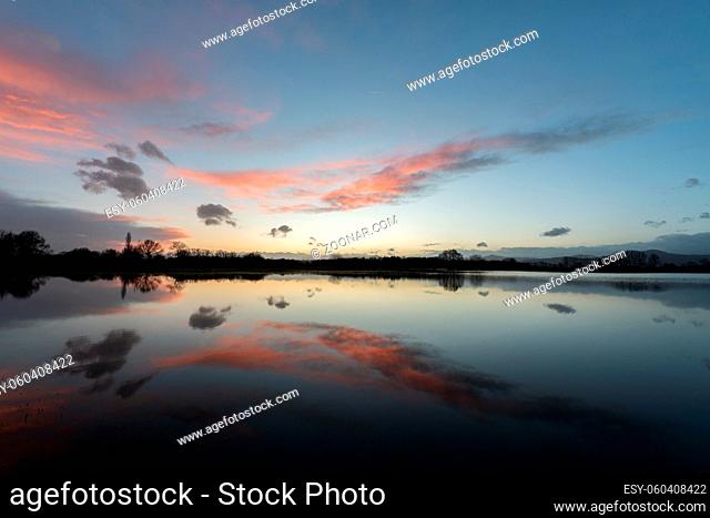 Meadow submerged in the flood during Sunset with perfect sky reflection