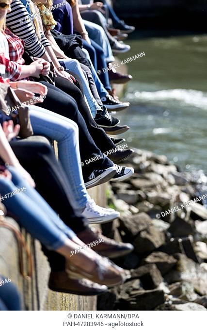 People sit on a wall at river Main during sunny weather in Wuerzburg, Germany, 20 March 2014. Photo: DANIEL KARMANN/dpa | usage worldwide