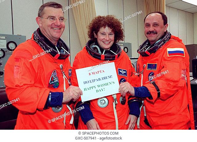 03/08/2001 --- STS-102 Mission Specialists James Voss, Susan Helms and Yury Usachev hold up a sign after donning their launch and entry suits