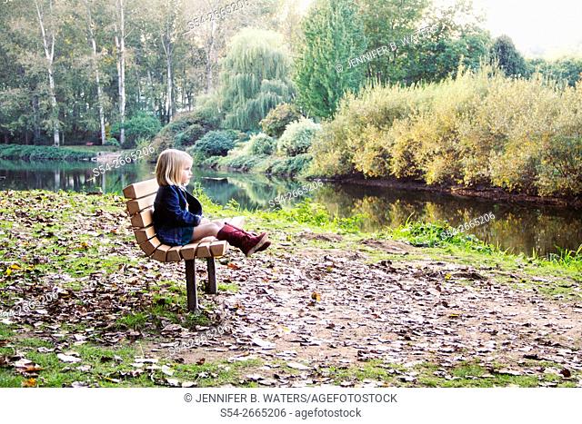A little girl sitting on a bench outdoors in Bothell, Washington, USA