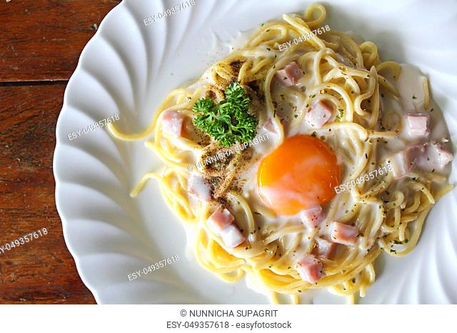 Spaghetti Carbonara with egg yolk on wooden table