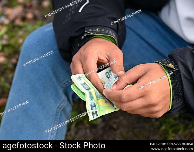 11 October 2023, Brandenburg, Roggosen: An unauthorized migrant holds euro banknotes in his hands after being apprehended by federal police officers near Forst...