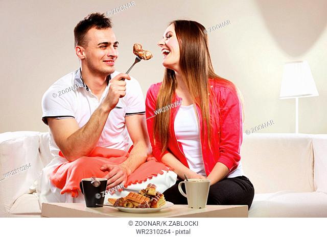 Smiling man feeding happy woman with cake