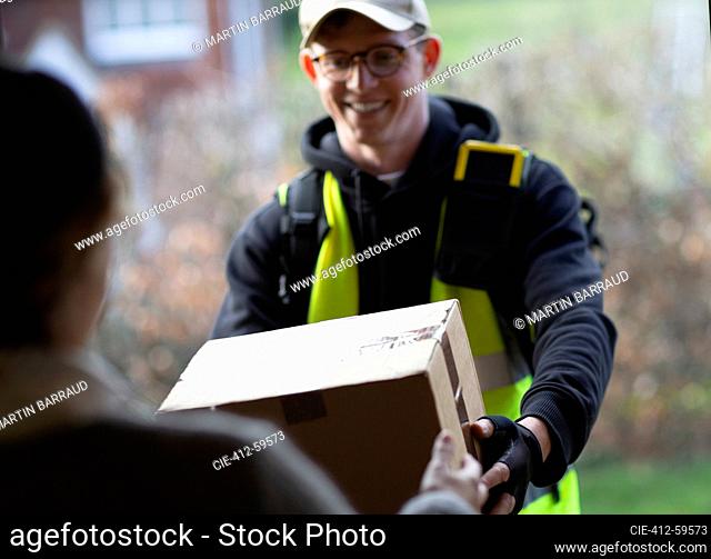 Friendly male courier delivering package at front door