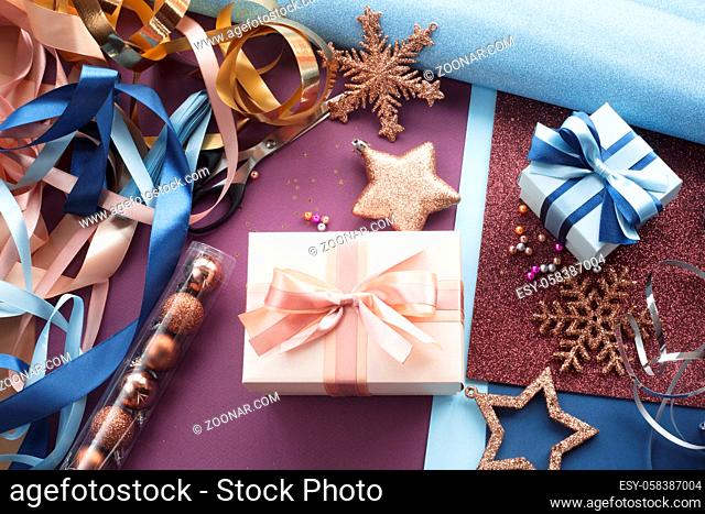 Workspace for gift wrapping, present boxes wrapped , paper ribbons balls baubles stars scissors glitters. Flat lay. Top view