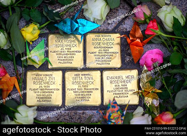 10 October 2023, Saxony-Anhalt, Magdeburg: Flowers and cranes folded from paper lie around five Stolpersteine that were laid there in memory of the Rosenheck...
