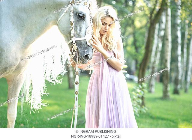 Blond cute woman with a white horse