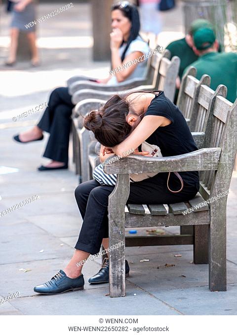 As the sun beats down, a woman falls asleep on a bench in the City of London near St Paul's Cathedral. Featuring: Atmosphere Where: London