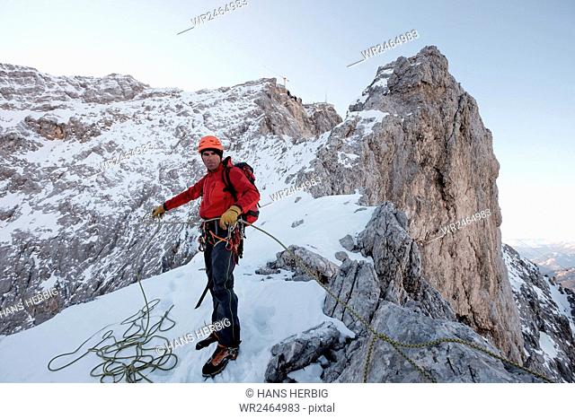 Mountain guide adjusting rope on cliff in mountain range