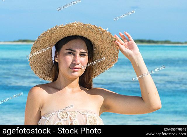Beautiful latin woman in blue bikini on tropical beach. Portrait of happy young woman smiling at sea. Brunette tanned girl in swimwear