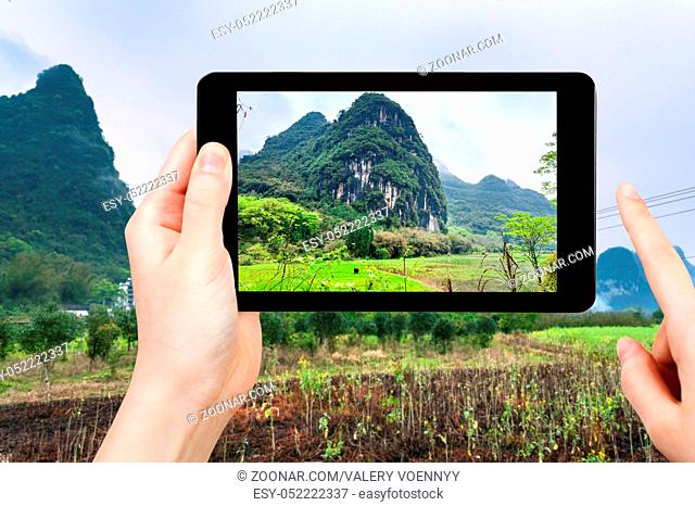 travel concept - tourist photographs gardens near karst mountains in Yangshuo County in spring season in China on smartphone -