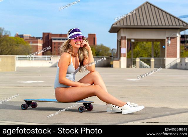 A gorgeous young blonde model enjoys a summer day with her skateboard
