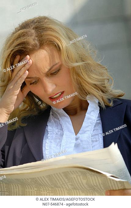Business woman reading a newspaper and getting bad news