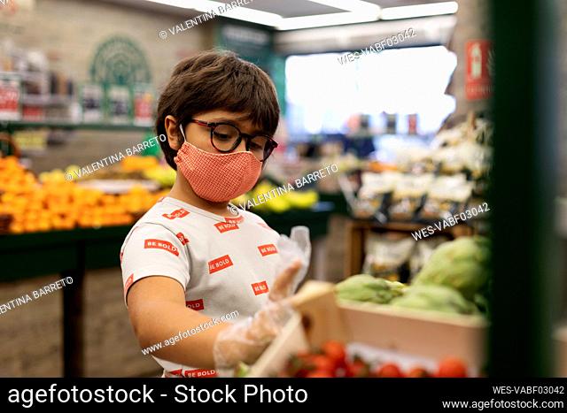 Boy taking vegetables in supermarket