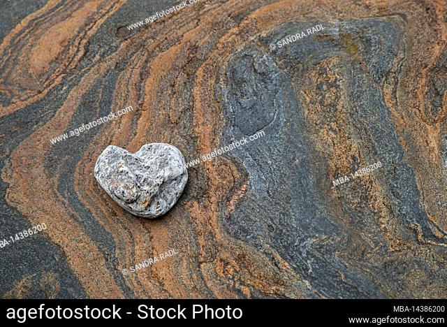 Stone in heart shape on colored structures in rock, Verzasca Valley, Switzerland, Canton Ticino