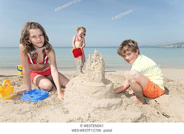 Spain, Mallorca, Children building sandcastle on beach