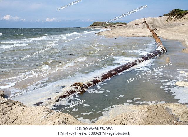 Big rustiy suction line pipes run over the beach in front of the camping dunes of the East Frisian Island Spiekeroog, Germany, 11 July 2017