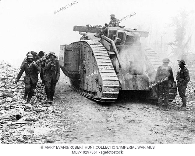 Tank moving to a forward area passing German stretcher bearers bringing in wounded on the Amiens Roye Road during the Battle of Amiens at the start of the...