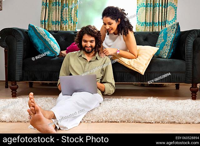 Young couple with curly hair watching laptop together at home