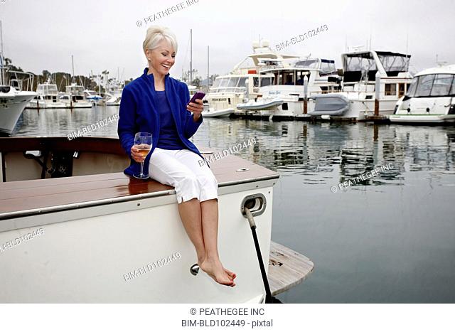 Woman sitting on boat text messaging on cell phone