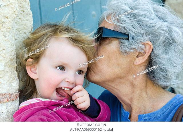 Grandmother kissing young granddaughter