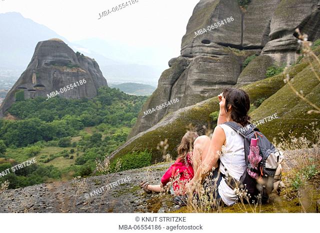 Panoramic picture of the rocky landscape around Meteora with woman and child sitting on ledge