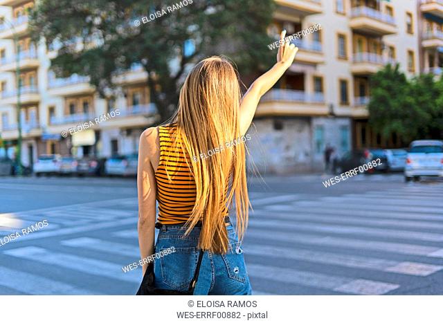 Spain, teenage girl hailing a taxi