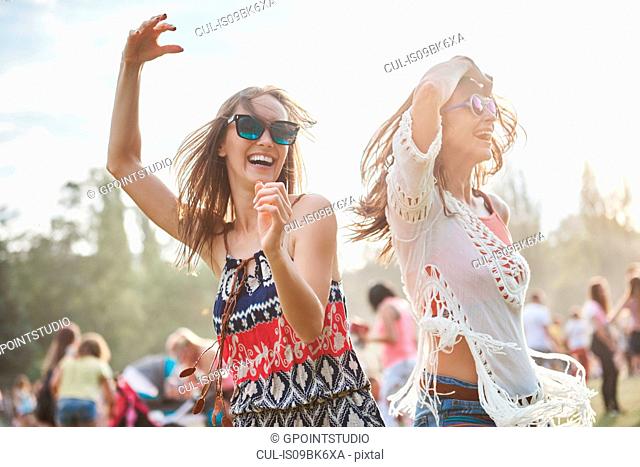 Friends dancing with arms raised in music festival