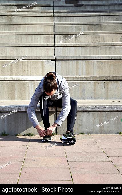 Man tying shoelace while sitting on steps