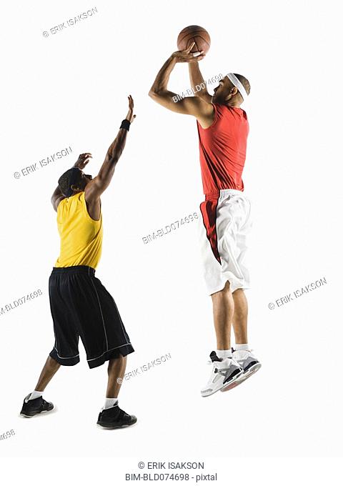 African man shooting basketball over opponent