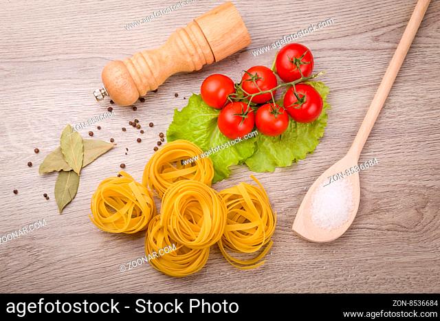 Pasta, tomatoes and pepper on a wooden background